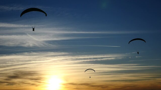 Personas realizando parapente al atardecer.