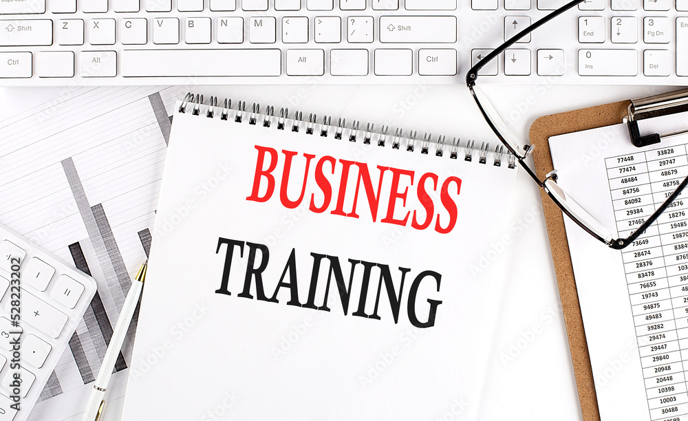 Aufkleber text business training on office desk table with keyboard, notepad and analysis chart on white backg