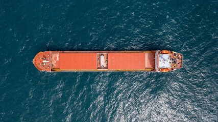Unloaded red cargo ship anchored in calm water.