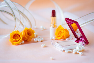 コスメとオレンジ色のバラと真珠とリボン（オレンジ色の背景）