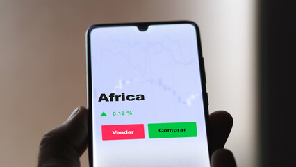 Un inversor está analizando el africa etf fondo en pantalla. Un teléfono muestra los precios del ETF AFRICA para invertir.