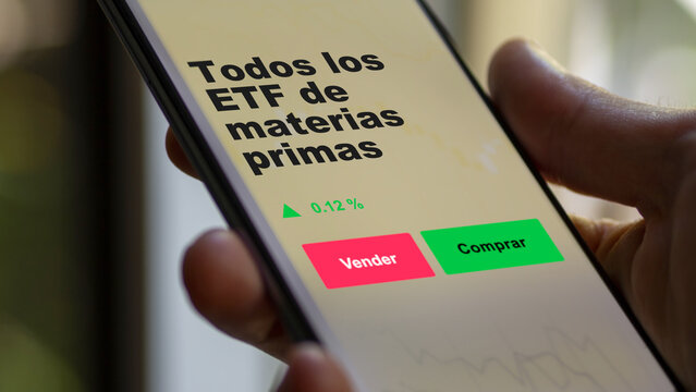 Un inversor est&aacute; analizando el todos los materias primas etf fondo en pantalla. Un tel&eacute;fono muestra los precios del ETF para invertir.