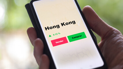 Un inversor está analizando el hong kong etf fondo en pantalla. Un teléfono muestra los precios...