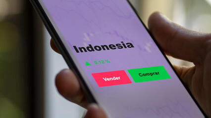 Un inversor está analizando el indonesia etf fondo en pantalla. Un teléfono muestra los precios...