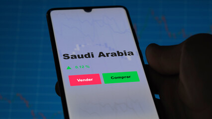 Un inversor está analizando el saudi arabia etf fondo en pantalla. Un teléfono muestra los...