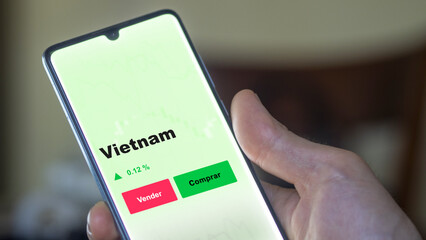 Un inversor está analizando el vietnam etf fondo en pantalla. Un teléfono muestra los precios del ETF VIETNAM para invertir.