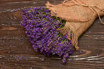 Obraz na płótnie Canvas Lovely bouquet of violet lavender wrapped in rough fabric napkin on the old brown table