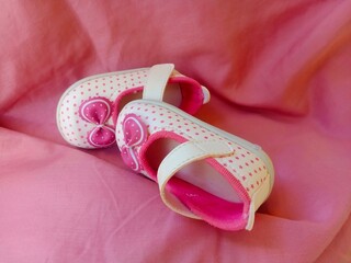 Cute pink baby shoes for little girl on blue background