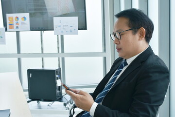 happy Asian business man using mobile phone in office room