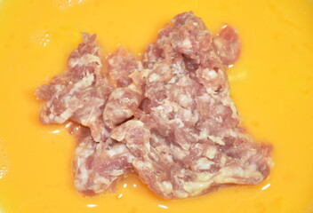 raw chop pork topping in egg yolk for cooking on plate