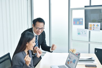 happy  busimess Asian man and woman looking at laptop screen with success moment in office