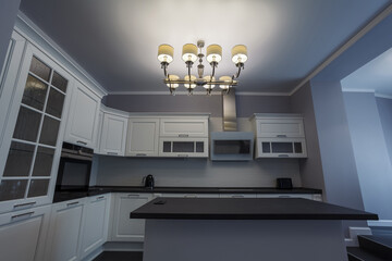 Fashionable kitchen with grey walls and white furniture, a kitchen in a modern classic style with granite countertop and bar island