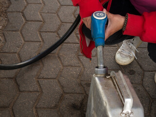 a girl pours gasoline into a metal canister from a pistol at a gas station