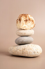 Creative concept sweet cotton candy pashmak stands on a stack of grey-colored marine spa stones. Pastel beige background