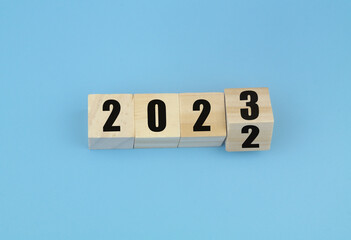 Wooden cubes with numbers 2023 on blue background. Flipping of 2022 to 2023.  New year concept.