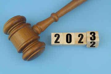 Wooden judge gavel and numbers 2023 and 2023 on wooden cubes. Concept of new laws in year 2023.