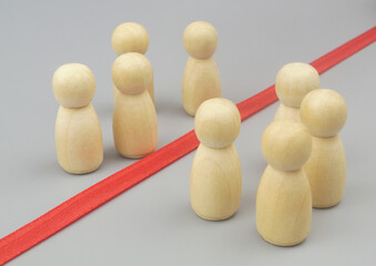 Obraz premium Separating people, borders between people concept. Wooden figures separated by red line or border.
