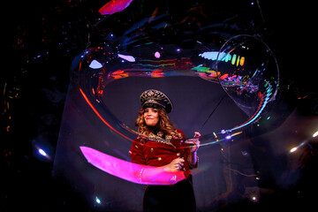 Woman magician illusionist circus in theatrical clothes stylish hat in shows soap bubbles show at...