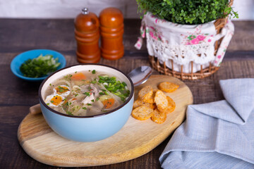 Soup with chicken, noodles, potatoes, quail eggs and carrots. Seasoned with onions and parsley. Close-up.