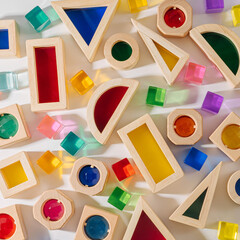 Wooden blocks with translucent rainbow stones on white background. Colorful toys for Kids.  Educational game for toddler. Play with light and exploring coloured shadows.
