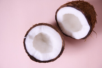 Close-up. Still life. Two halves of ripe organic raw vegan coconuts, shot with soft shadow on pink background copy space