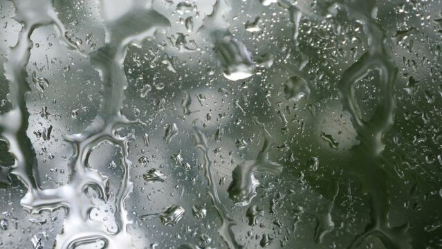 Detalle de gotas de lluvia desliz&aacute;ndose sobre el cristal de un coche en un d&iacute;a de tormenta.