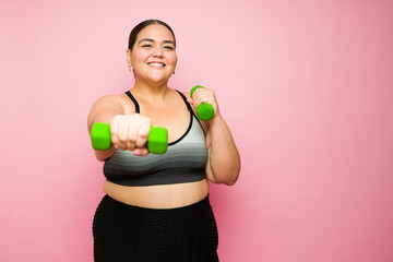 Portrait of an active fat woman working out with weights and smiling