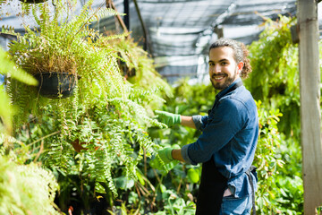 Naklejka na ściany i meble Happy young man feeling proud of his beautiful green plants