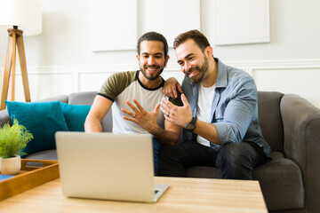 Gay couple getting married showing their engagement rings to family on a video call