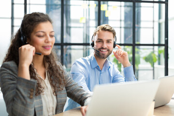 Portrait of call center worker accompanied by his team. Smiling customer support operator at work.