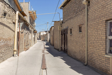 Residential area in old city with brick houses behind walls along narrow street, Bukhara, Uzbekistan