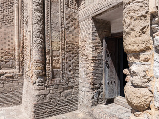 Entrance to ancient religious building with brick walls and carved wooden door, Bukhara, Uzbekistan
