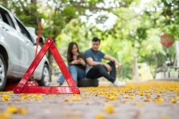 Asian couple using smartphone for assistance after a car breakdown on street. Concept of vehicle engine problem or accident and emergency help from Professional mechanic