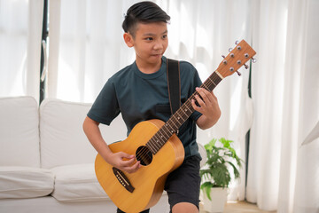 Portrait of a Asian happy smiling boy having fun playing guitar Music concept, kids music school. Rock concert,  Music for kids and toddlers concept