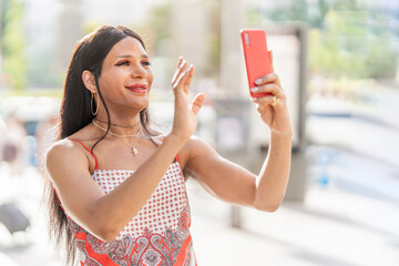 Trans woman waving at the mobile while doing video call