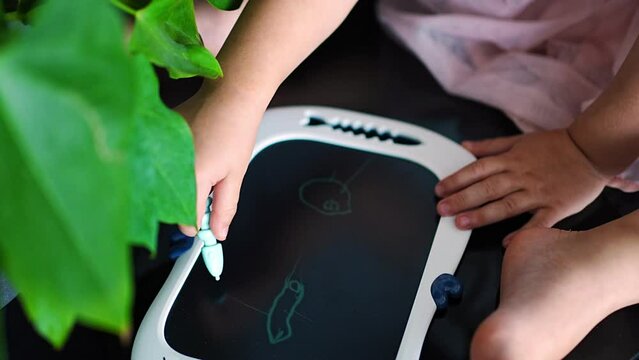 Little girl is drawing on Led tablet at home. Close up view of child hand with painting scribble