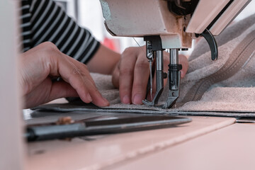 The seamstress sews at the sewing machine, threads the fabric. Women's hands