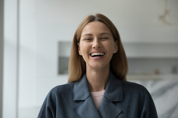 Happy beautiful 30s Caucasian woman wearing grey coat, looking at camera, smiling, laughing. Cheerful attractive lady, dental clinic patient, fashion shop customer head shot portrait