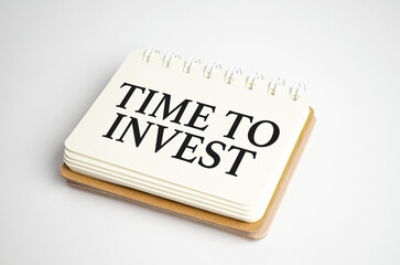 TIME TO INVEST text written on notebook on grey background