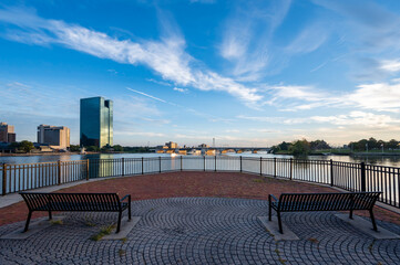 Reflection of downtown Toledo Ohio skyline during sunrise from international park with a foreground of two benches and brick patterns 