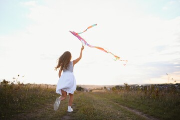 Fototapeta na wymiar one happy little girl running on field with kite.