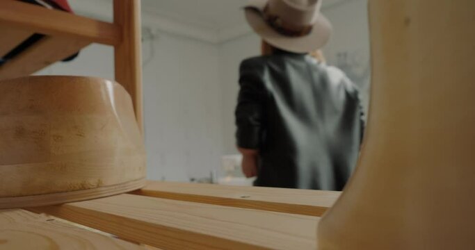 Professional milliner takes wooden mold standing on shelf