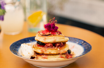 Appetizing pancakes decorated with berries and flowers.