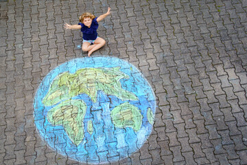 Little preschool girl with earth globe painting with colorful chalks on ground. Positive toddler child. Happy earth day concept. Creation of children for saving world, environment and ecology.