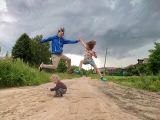 A father jumping with kids. Parent and sons in summer. Funny family photo. Country summer landscape. 