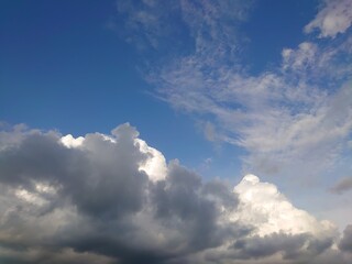 Fototapeta na wymiar Bright deep blue sky with big white fluffy clouds. Glowing summer sky photo background.