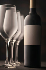 A bottle of red wine and three beautiful empty crystal glasses close-up. Atmospheric still life in a low key.