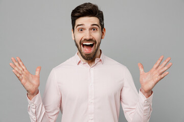 Young fun surprised shocked amazed ipressed caucasian man 20s he wearing basic white shirt spread hands look camera isolated on plain grey color background studio portrait. People lifestyle concept.