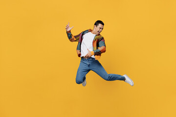 Fototapeta na wymiar Full body young fun middle eastern man 20s wear casual shirt white t-shirt jump high pretending play guitar hand gesture isolated on plain yellow background studio portrait People lifestyle concept