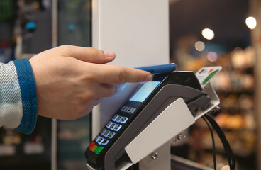 Close up of male hand holding smartphone in payment terminal.